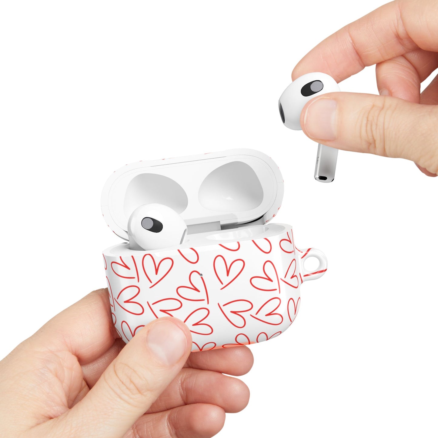 Hands holding white AirPods case with red heart design, one AirPod being removed to show case functionality and user-friendly grip