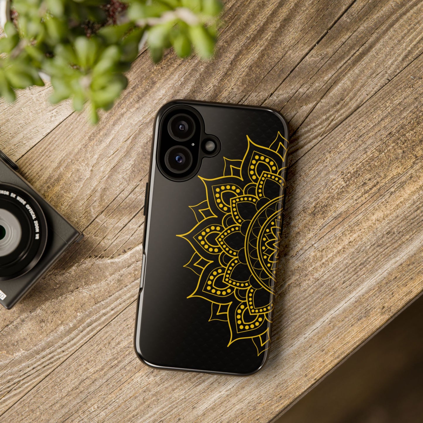 Stylish black iPhone case with intricate gold mandala design – flat lay on rustic wooden table